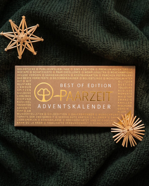 Paarzeit Adventskalender BEST OF EDITION aus Kraftpapier mit goldener Schrift, auf dunkelgrünem Strickstoff zwischen zwei Strohsternen