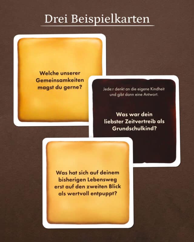 Drei keksförmige Fragekarten auf dunkelbraunem Untergrund: „Welche unserer Gemeinsamkeiten magst du gerne?“, „Was war dein liebster Zeitvertreib als Grundschulkind?“ und „Was hat sich auf deinem bisherigen Lebensweg erst auf den zweiten Blick als wertvoll entpuppt?“