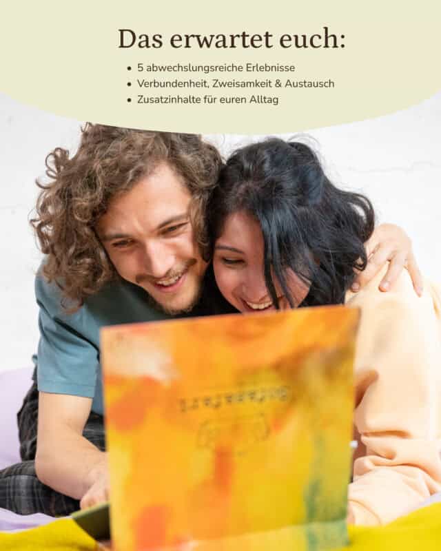 Ein Mann und eine Frau liegen eng beieinander und schauen lächelnd auf die geöffnete, orange-gelb aquarellierte Sofasafari-Box im Vordergrund